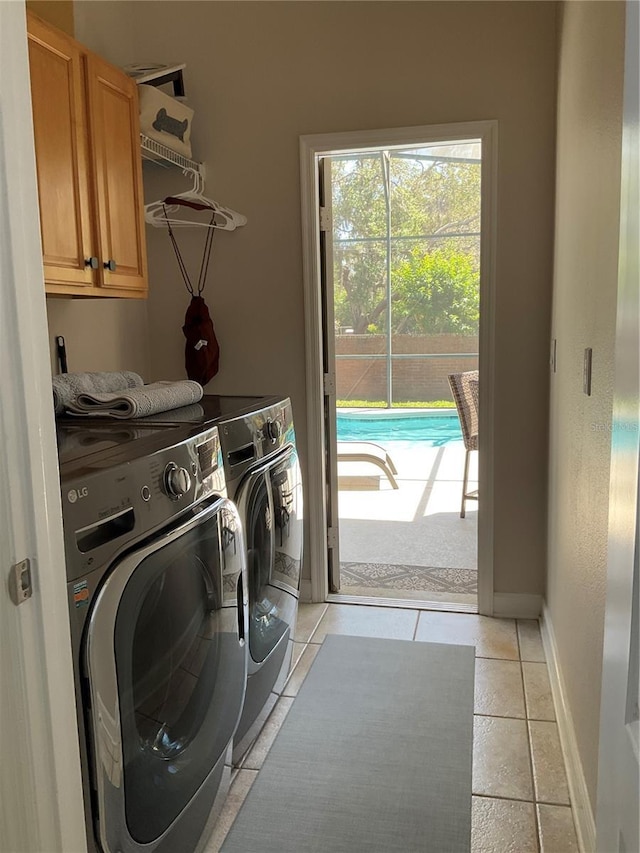 clothes washing area featuring washing machine and dryer, baseboards, light tile patterned floors, and cabinet space