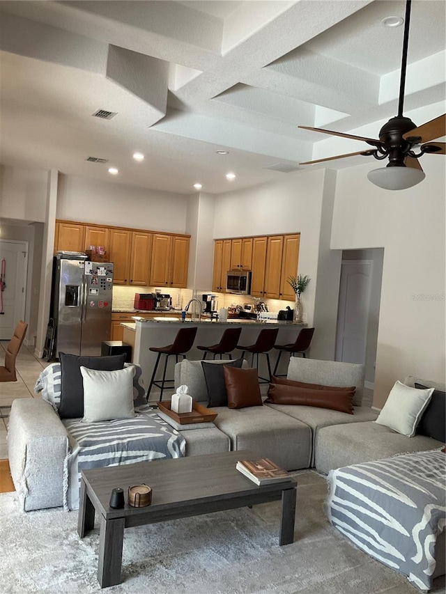 living room with recessed lighting, visible vents, a ceiling fan, and a high ceiling