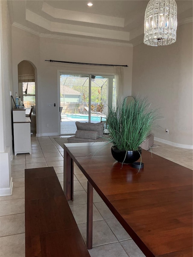 dining area featuring a tray ceiling, arched walkways, and a healthy amount of sunlight