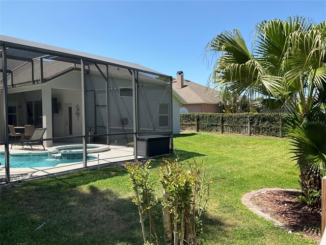 view of yard featuring fence, a patio area, a lanai, and a pool with connected hot tub