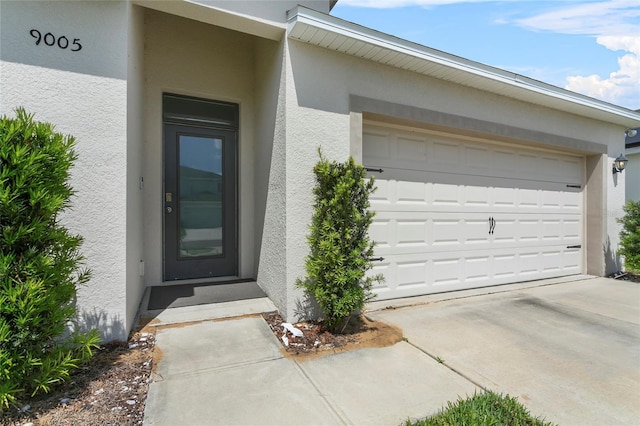 9005 Tuscan Cypress St, Kissimmee, FL 34747 - property entrance with stucco siding, concrete driveway, and an attached garage