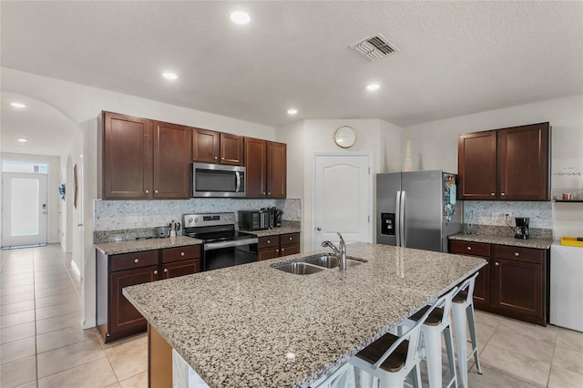 9005 Tuscan Cypress St, Kissimmee, FL 34747 - kitchen featuring appliances with stainless steel finishes, light tile patterned floors, decorative backsplash, a kitchen bar, and recessed lighting
