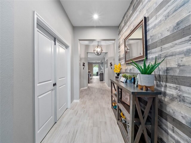 1151 Lakeside Estates Dr, Apopka, FL 32703 - hall with an inviting chandelier, wood walls, baseboards, and light wood-type flooring