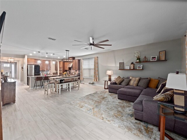 1151 Lakeside Estates Dr, Apopka, FL 32703 - living room with light wood finished floors, ceiling fan with notable chandelier, visible vents, and baseboards