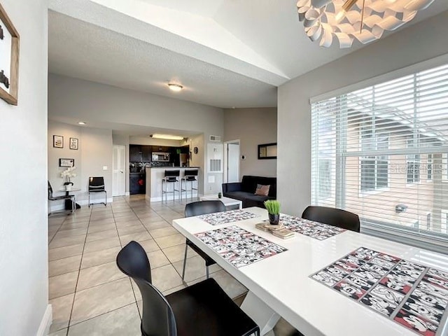 dining room featuring light tile patterned floors, lofted ceiling, and baseboards