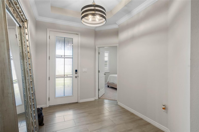 foyer featuring baseboards, crown molding, a notable chandelier, and a raised ceiling