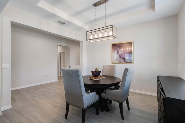 dining space with a tray ceiling, baseboards, and visible vents
