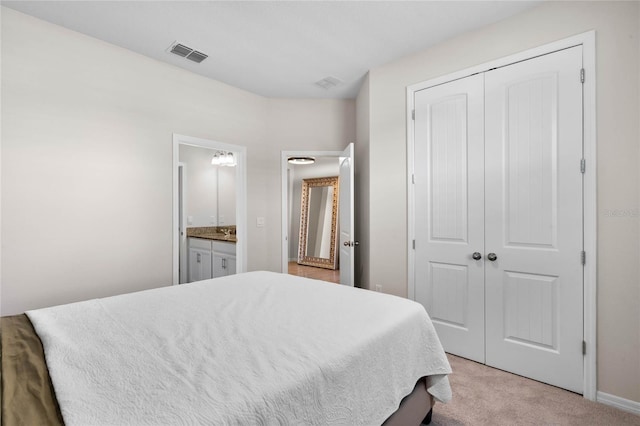 bedroom featuring ensuite bathroom, a closet, light colored carpet, and visible vents