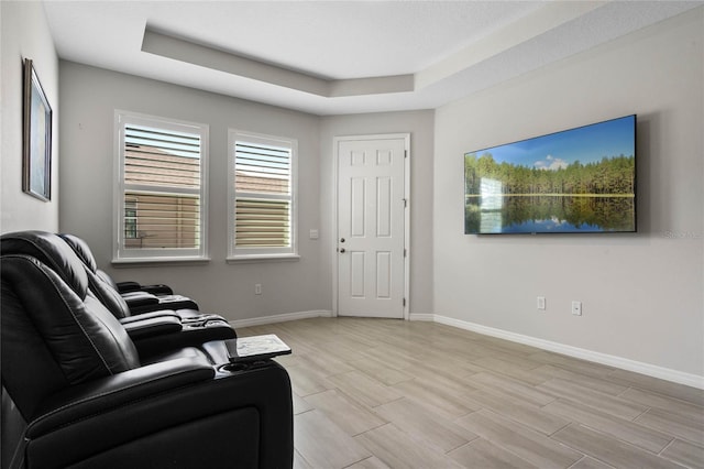 living area with a raised ceiling, baseboards, and wood tiled floor