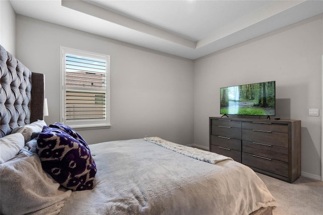 bedroom featuring baseboards, a tray ceiling, and light carpet