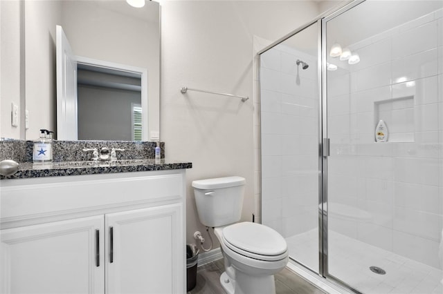 full bathroom featuring baseboards, toilet, a stall shower, and vanity