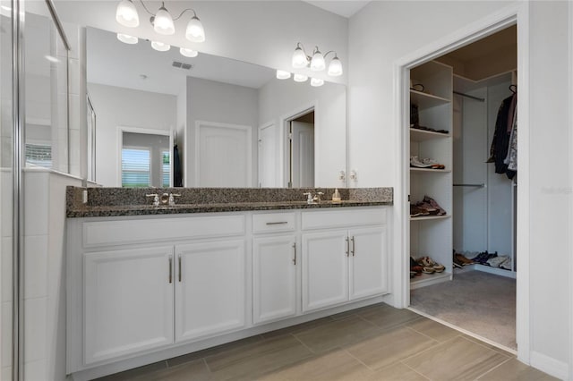 bathroom with double vanity, visible vents, a spacious closet, and a sink