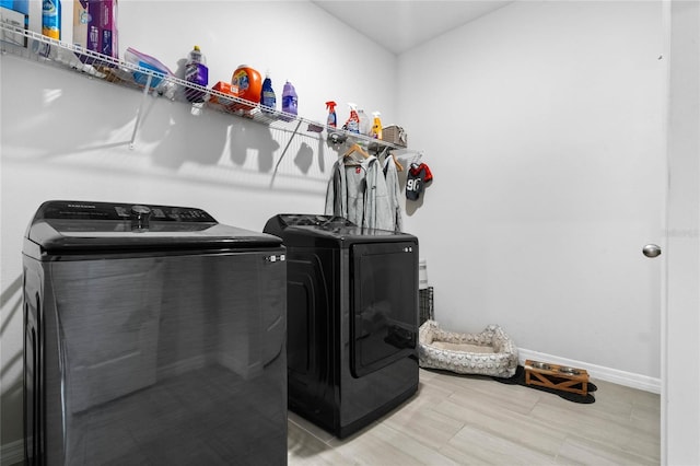 clothes washing area featuring baseboards, washing machine and clothes dryer, and laundry area