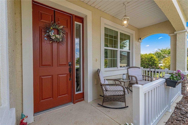 view of exterior entry featuring a porch and stucco siding