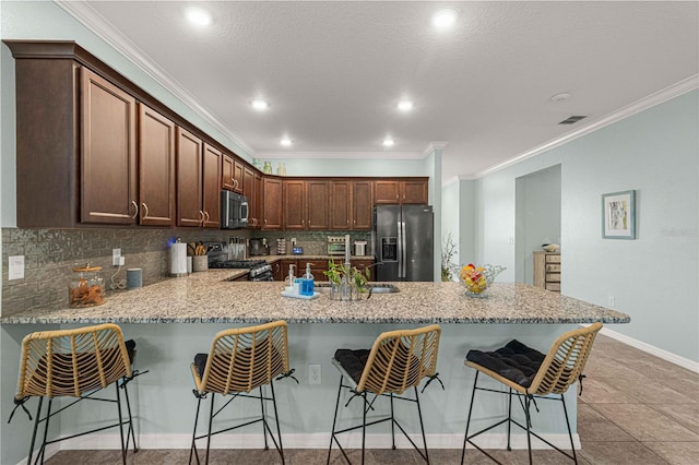 kitchen with a peninsula, decorative backsplash, crown molding, and stainless steel appliances