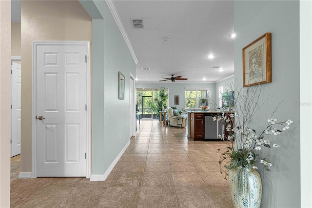 hallway with crown molding, baseboards, visible vents, and arched walkways