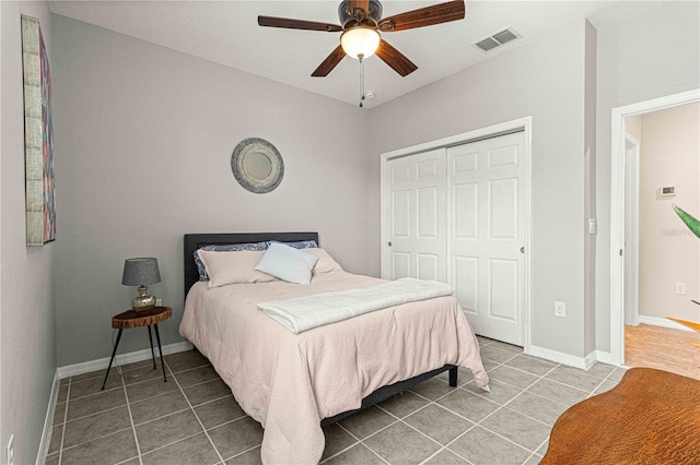 bedroom featuring a closet, a ceiling fan, visible vents, tile patterned floors, and baseboards