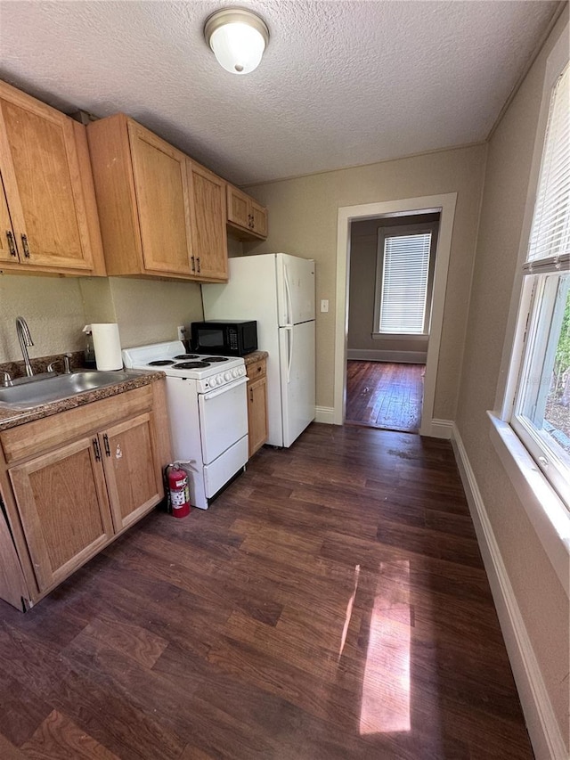 kitchen with a sink, a textured ceiling, white appliances, dark wood finished floors, and baseboards