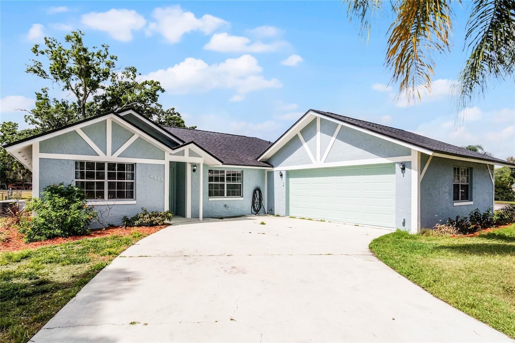 4415 London Town Rd, Titusville, FL 32796 - view of front of house featuring stucco siding, roof with shingles, an attached garage, driveway, and a front lawn