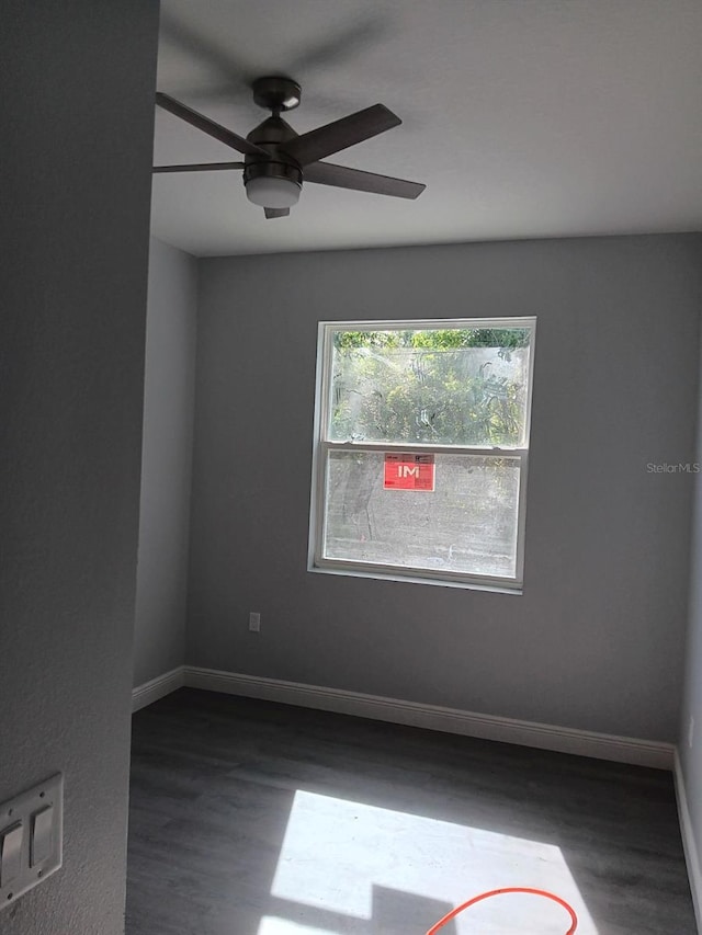 spare room with ceiling fan, baseboards, and dark wood finished floors