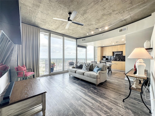 living area with floor to ceiling windows, a ceiling fan, visible vents, and wood finished floors
