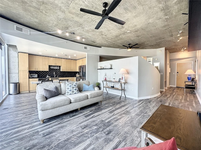 living area with baseboards, visible vents, light wood-style floors, and ceiling fan