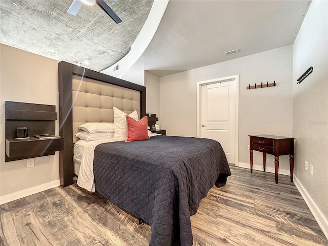 bedroom with baseboards, visible vents, and wood finished floors