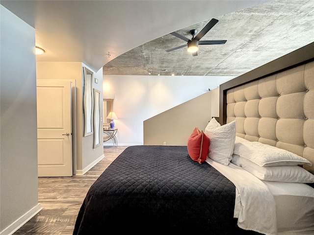 bedroom with baseboards, rail lighting, wood finished floors, and a ceiling fan