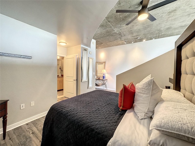 bedroom with baseboards, rail lighting, and wood finished floors