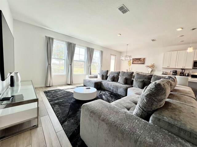 832 Benoi Dr, Davenport, FL 33896 - living room with baseboards, visible vents, light wood-style flooring, and an inviting chandelier