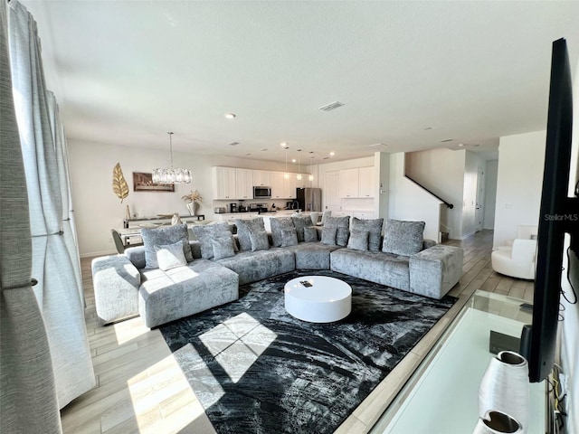 832 Benoi Dr, Davenport, FL 33896 - living room featuring stairs, visible vents, light wood-style floors, and a notable chandelier