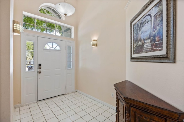 foyer featuring baseboards, a towering ceiling, and light tile patterned floors