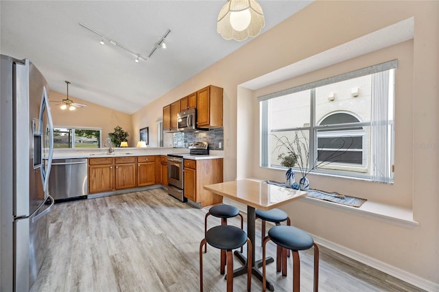 kitchen featuring light countertops, a sink, stainless steel appliances, and brown cabinetry