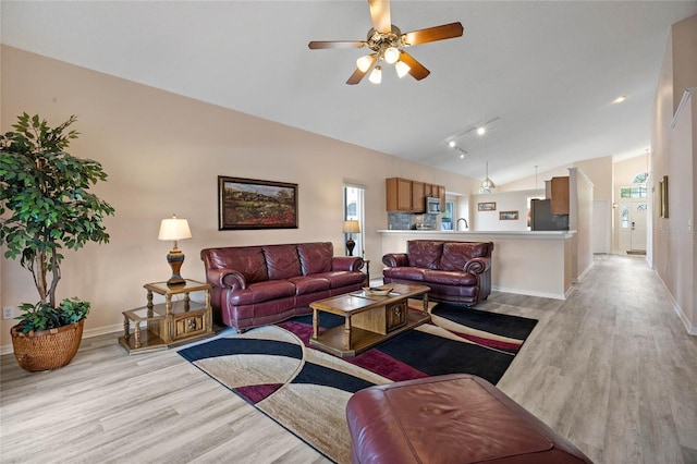 living room with baseboards, vaulted ceiling, light wood-style floors, and a ceiling fan