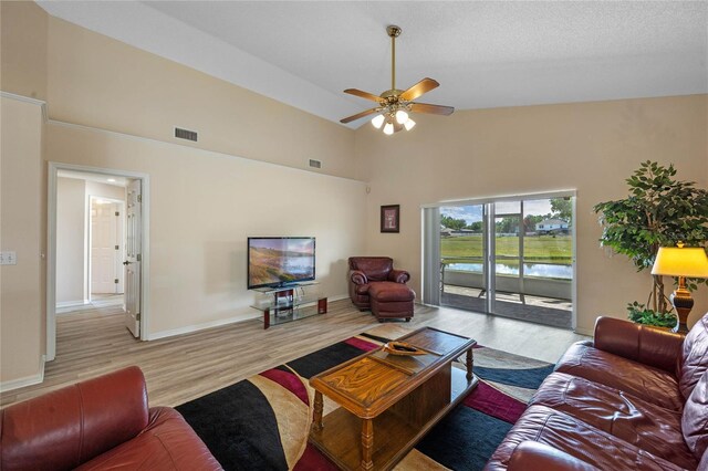 living area with light wood finished floors, visible vents, high vaulted ceiling, and ceiling fan