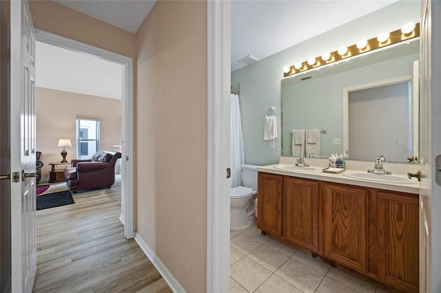 bathroom with toilet, a sink, double vanity, and visible vents