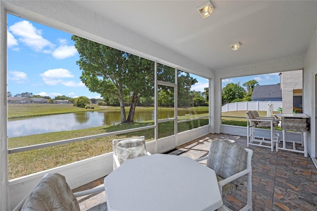 sunroom featuring outdoor dining area and a water view