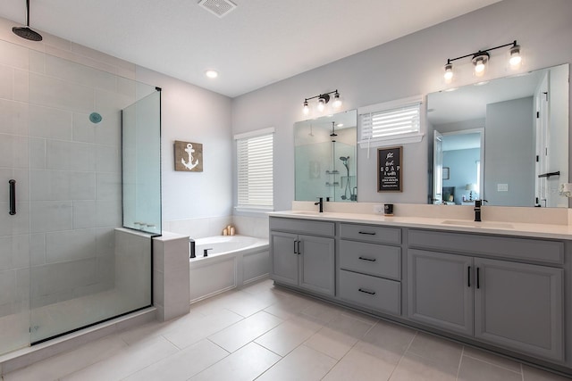 bathroom with visible vents, a shower stall, double vanity, a sink, and a garden tub