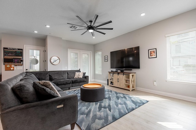 living area with wood finished floors, visible vents, a healthy amount of sunlight, and ceiling fan
