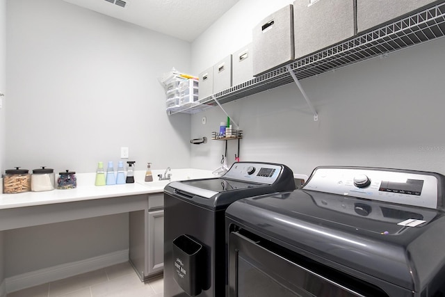 laundry area with light tile patterned flooring, baseboards, laundry area, a sink, and separate washer and dryer