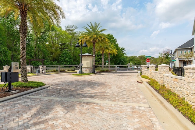 view of road featuring street lights, a gated entry, a gate, and traffic signs