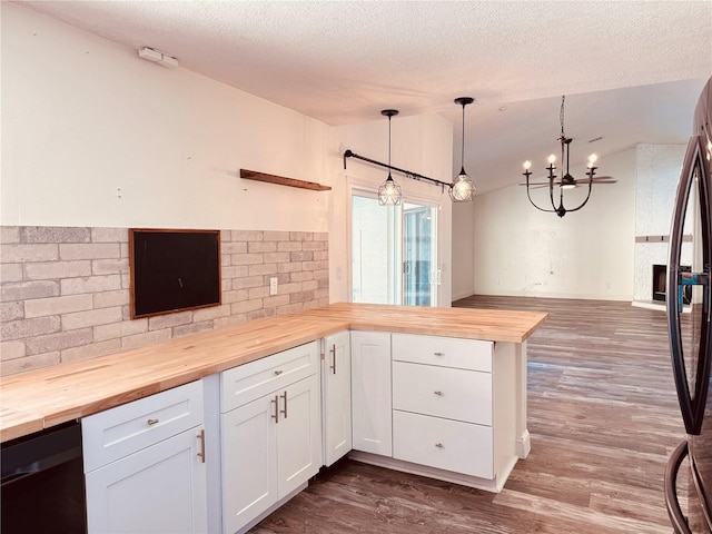 7808 The Esplanade Ct, Orlando, FL 32836 - kitchen with butcher block counters, a peninsula, vaulted ceiling, white cabinets, and dark wood-style flooring