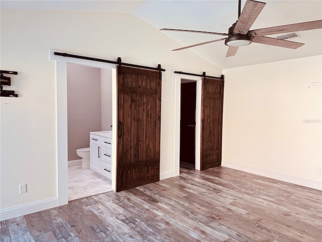7808 The Esplanade Ct, Orlando, FL 32836 - unfurnished bedroom with a barn door, lofted ceiling, light wood-type flooring, connected bathroom, and ceiling fan
