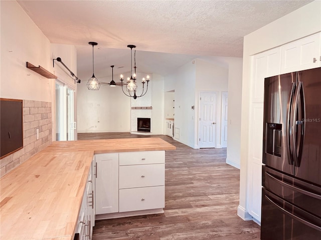7808 The Esplanade Ct, Orlando, FL 32836 - kitchen featuring stainless steel refrigerator with ice dispenser, butcher block counters, a peninsula, lofted ceiling, and a fireplace