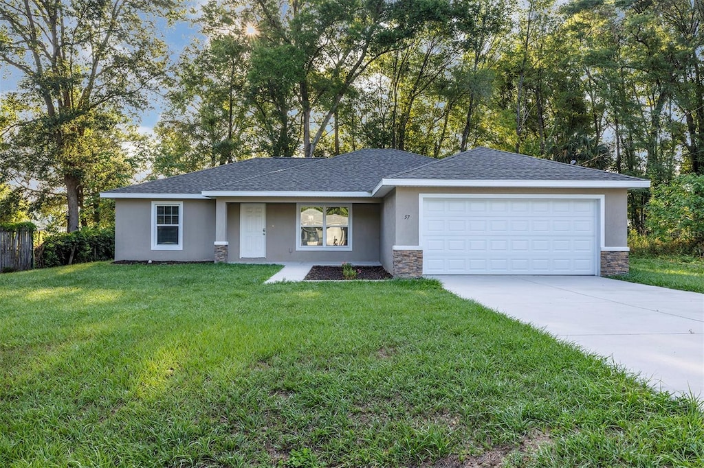 single story home with driveway, an attached garage, stucco siding, a front yard, and stone siding