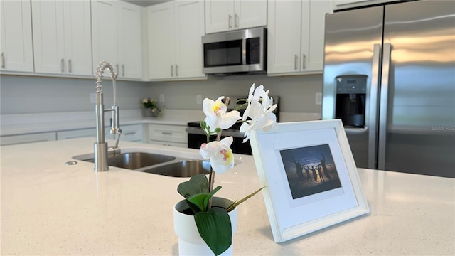 6345 SW 155th Pl, Ocala, FL 34473 - kitchen with stainless steel appliances, a sink, white cabinetry, and light stone countertops