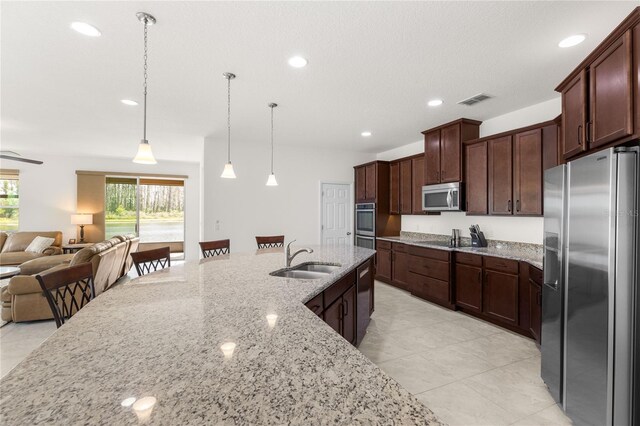 3936 Parkhouse Dr, Orlando, FL 32824 - kitchen featuring visible vents, appliances with stainless steel finishes, a sink, light stone counters, and open floor plan