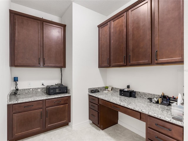 3936 Parkhouse Dr, Orlando, FL 32824 - kitchen featuring dark brown cabinetry, built in desk, and light stone counters