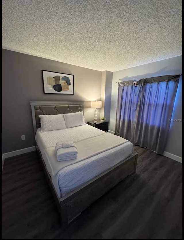 bedroom featuring baseboards, wood finished floors, and a textured ceiling