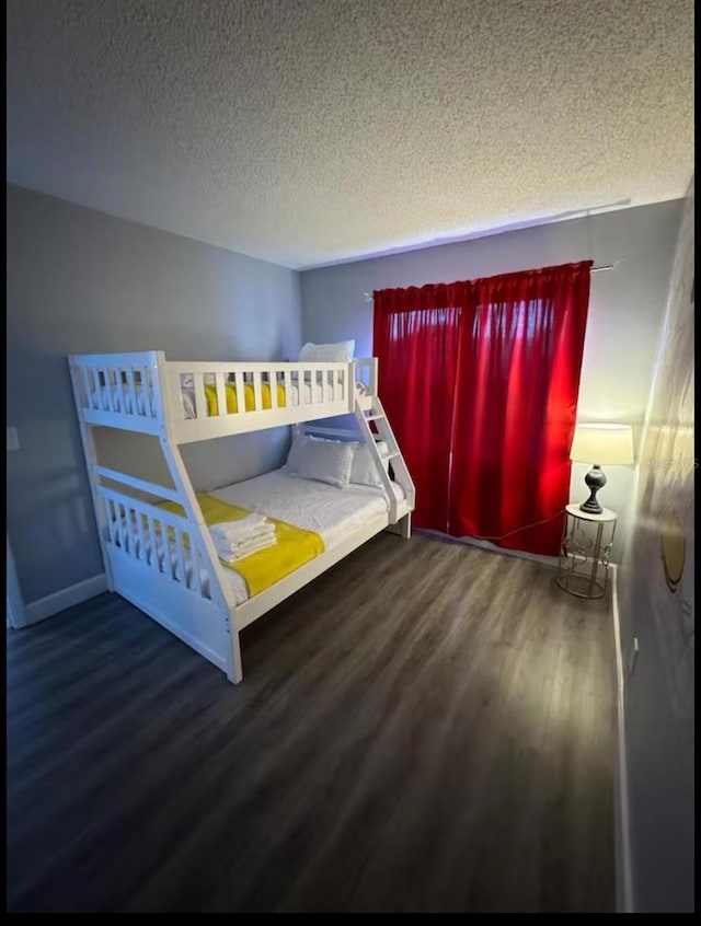 unfurnished bedroom with baseboards, wood finished floors, and a textured ceiling